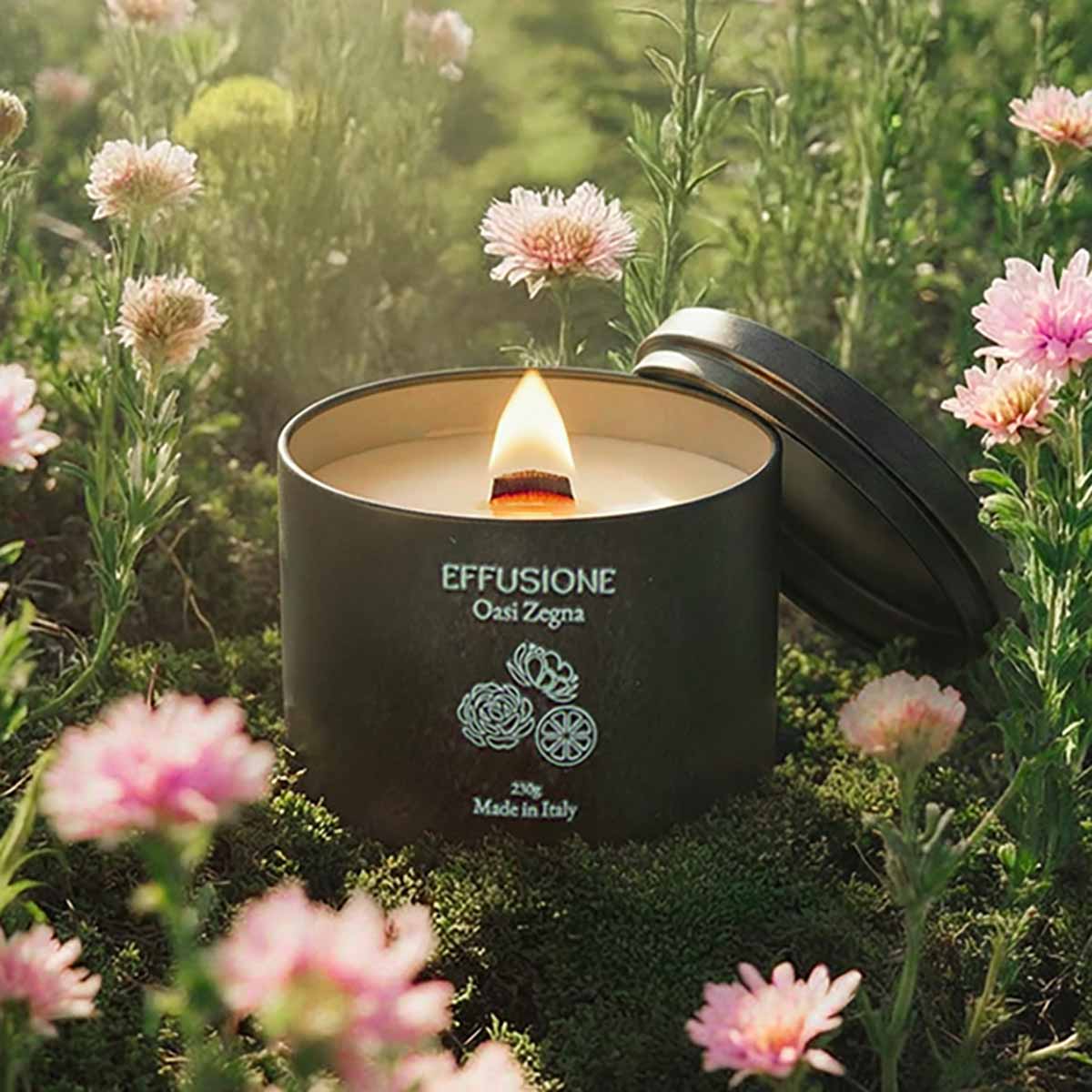 Candela profumata Effusione Oasi Zegna accesa tra fiori e natura