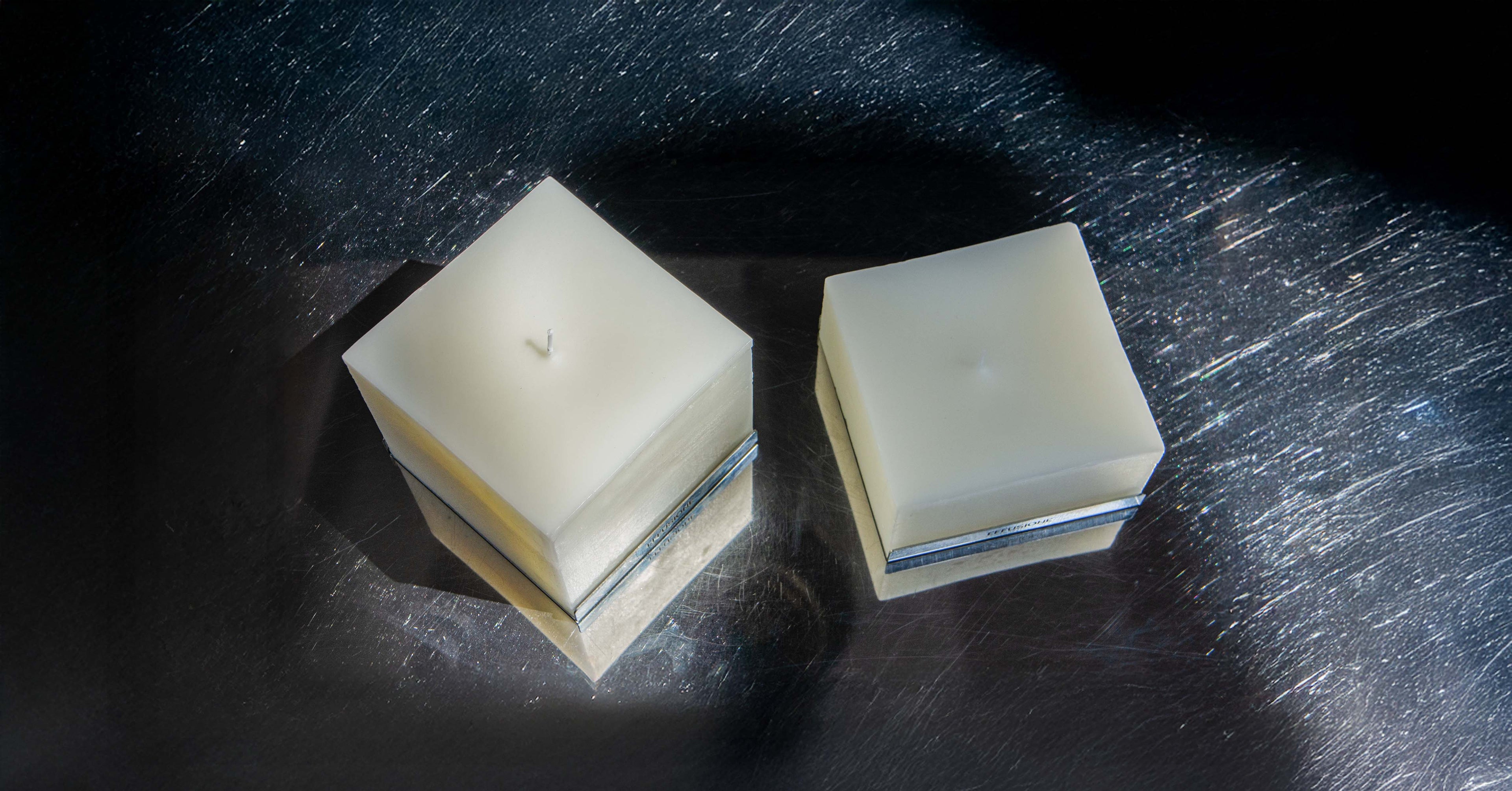 Candele quadrate Collezione Eterna dal design minimal non profumate su superficie metallica