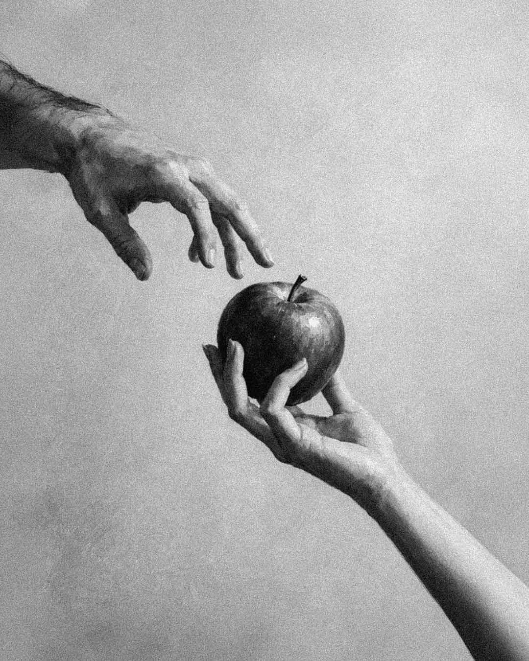 Due mani si tendono verso una mela, simbolo di tentazione, ispirate alla fragranza Eden di Aura Effusione.