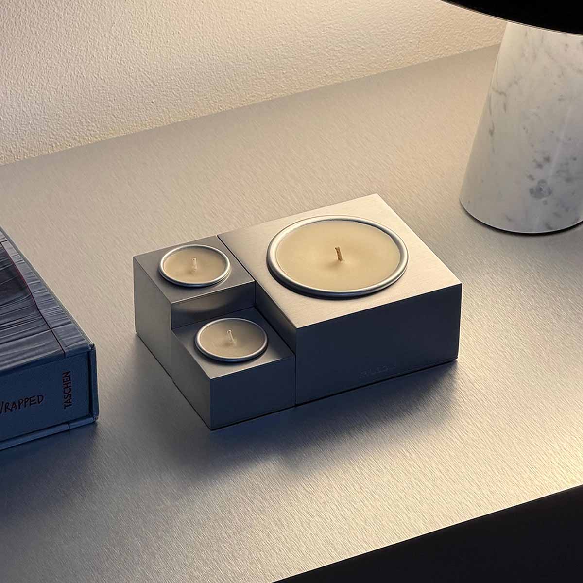 Candela Aura Effusione in alluminio dal design modulare su tavolo contemporaneo.