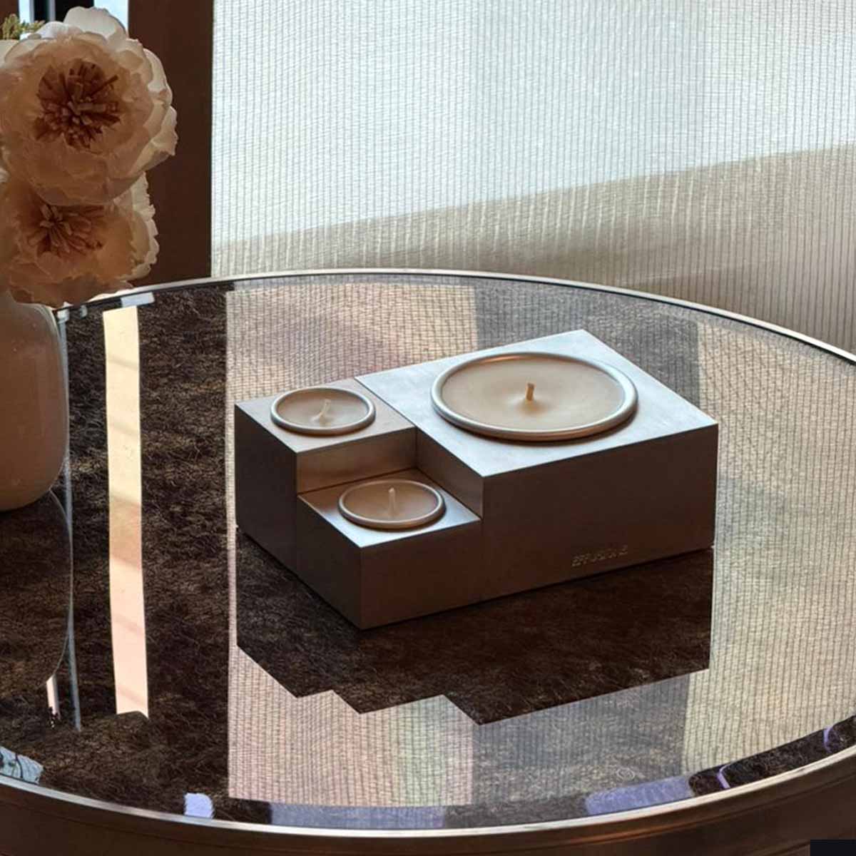 Candela magnetica modulare Aura Effusione fragranza Baraggia in alluminio su tavolo di design.