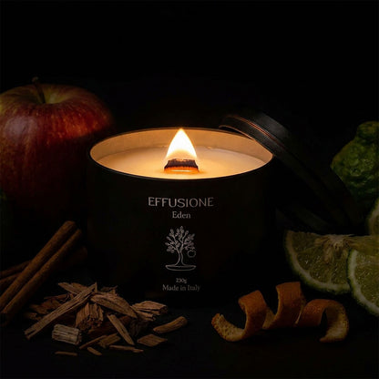 Candela profumata Eden di Effusione accesa, circondata da mela, agrumi, cannella e legni aromatici.