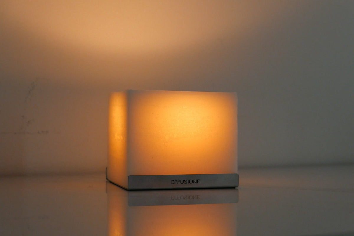 Candela scultorea Eterna Effusione illuminata con riflesso su superficie lucida